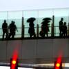 Photo: Some pedestrians carrying umbrellas, cross a foot Photo: Some pedestrians carrying umbrellas, cross a foot