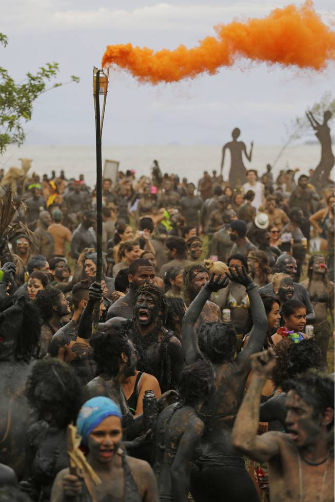 Gangs of mud-covered revelers dance during the "Bloco da Lama" or "mud street party" in Paraty, Brazil, Saturday, March 1, 2014. Extravagant costumes need not apply at the "Bloco da Lama" Carnival street party, where revelers dispense with pirate, princess and devil disguises in favor of a thick, head-to-toe layers of black mud.