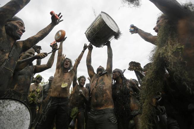 Mud-covered revelers dance and sing at the "Bloco da Lama" or "mud street party" beneath an overcast sky in Paraty, Brazil, Saturday, March 1, 2014. The "Bloco da Lama" was founded in 1986 by two local teens who became local Carnival sensations after they appeared in the city's historic downtown covered in mud following a crab hunting expedition in a nearby mangrove forest, said Diana Rodrigues, who was hired by Paraty's City Hall to explain the history of the "bloco" to foreigners.