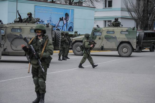 Troops in unmarked uniforms stand guard as they take control of the Coast Guard offices in Balaklava on the outskirts of Sevastopol, Ukraine, Saturday, March 1, 2014. An emblem on one of the vehicles and their number plates identify them as belonging to the Russian military. Ukrainian officials have accused Russia of sending new troops into Crimea, a strategic Russia-speaking region that hosts a major Russian navy base.