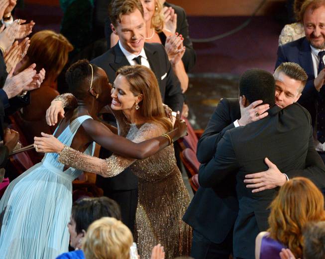 Lupita Nyong'o, left, is embraced by Angelina Jolie, and Brad Pitt embraces Chiwetel Ejiofor as they celebrate in the audience after "12 Years a Slave" was announced the winner for best picture during the Oscars at the Dolby Theatre on Sunday, March 2, 2014, in Los Angeles. (Photo by John Shearer/Invision/AP)
