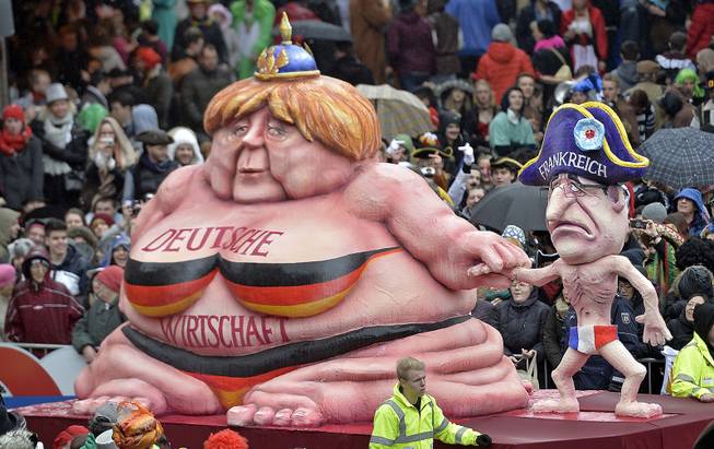 A carnival float caricating German chancellor Angela Merkel, left, representing the growing German economy, and a slim French president Francois Hollande during the traditional carnival parade in Duesseldorf, western Germany, on Monday, March 3, 2014. The foolish street spectacles in the carnival centers of Duesseldorf, Mainz and Cologne, watched by hundreds of thousands of people, are the highlights in Germany's carnival season on Rose Monday. Words at left read: German Economy.