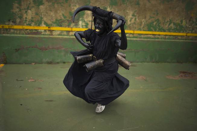 A woman, covered in oil and soot carrying bull horns on his head and cowbells on a belt representing the devil, runs while participating in carnival celebrations in the small village of Luzon, Spain, Saturday, March 1, 2014. Preserved records from the 14th century document Luzon's carnival, but the real origin of the tradition could be much older. Carnival festivals are celebrated in their own way around hundreds of villages in Spain.