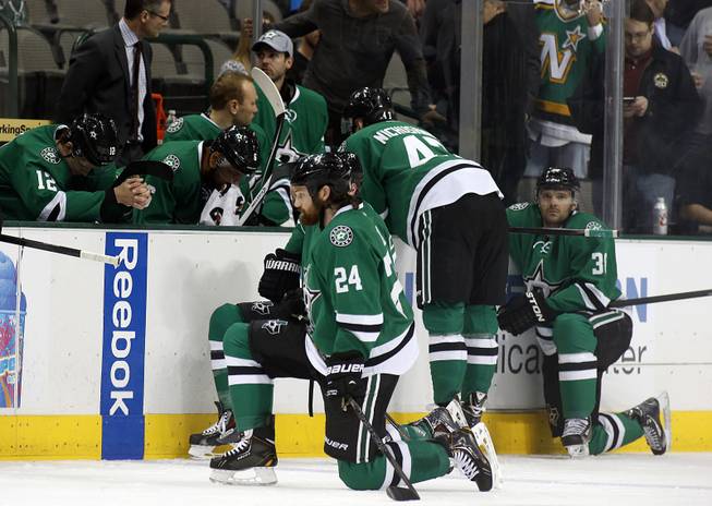 Dallas Stars right wing Alex Chiasson (12) bows his head on the bench as defenseman Jordie Benn (24) takes a knee on the ice after play was stopped in the first period of an NHL Hockey game against the Columbus Blue Jackets, Monday, March 10, 2014, in Dallas. Stars center Rich Peverly was taken to a hospital after a medical emergency.