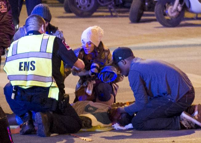 Bystanders and paramedics tend to a person who was struck by a vehicle on Red River Street in downtown Austin, Texas, at SXSW on Wednesday, March 12, 2014. Police say a man and woman have been killed after a suspected drunken driver fleeing from arrest crashed through barricades set up for the South By Southwest festival and struck the pair and others on a crowded street.