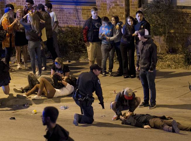 A bystander and a police officer tend to a man who was struck by a vehicle on Red River Street in downtown Austin, Texas, at SXSW on Wednesday March 12, 2014. Police say a man and woman have been killed after a suspected drunken driver fleeing from arrest crashed through barricades set up for the South By Southwest festival and struck the pair and others on a crowded street.