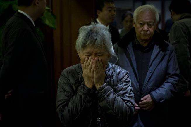 An elderly woman, one of the relatives of Chinese passengers aboard missing Malaysia Airlines Flight MH370, covers her face out of frustration as she leaves a hotel ballroom after a daily briefing meeting with managers of Malaysia Airlines in Beijing, China, Wednesday, March 19, 2014.