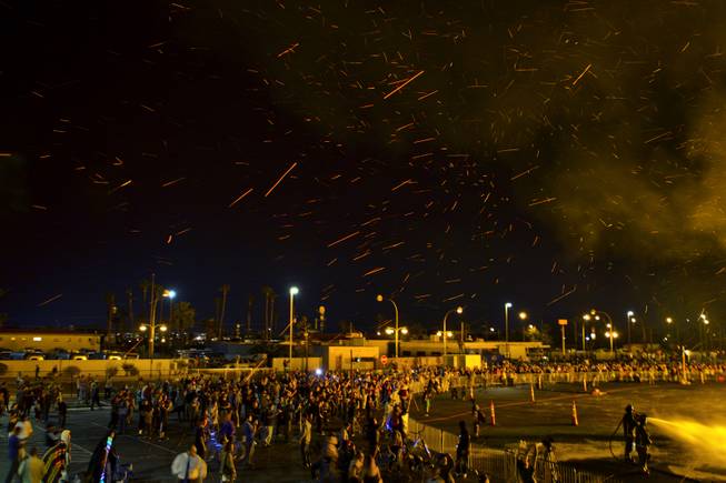 Cinders fly in the wind as Life Cube, an interactive community art installation, goes up in flames in downtown Las Vegas, Friday March 21, 2014. The Life Cube, a creation of artist Scott Cohen, was a 24-by-24-foot plywood cube, painted by artists and filled with notes from thousands of people.