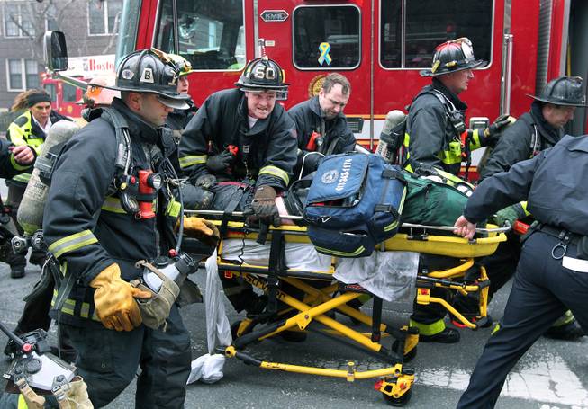 Firefighters scream for an ambulance as they work on and rush an injured firefighter on a stretcher down Beacon Street, Wednesday, March 26, 2014, in Boston. Firefighters responded to a four-story brownstone fire. A Boston city councilor said two firefighters have died in the fire.