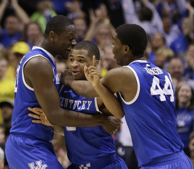 Kentucky's Aaron Harrison, center, is congratulated by teammates Julius Randle, left, and Dakari Johnson after making a 3-point basket in the final seconds of the second half of the NCAA Midwest Regional final game against Michigan on Sunday, March 30, 2014, in Indianapolis. Kentucky won 75-72 to advance to the Final Four.