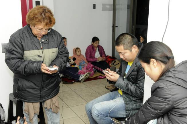 People use their phones on the upper floor of an apartment building located a few blocks from the coast where they gathered to avoid a possible tsunami after an earthquake in Iquique, Chile, Tuesday, April 1, 2014. A powerful magnitude-8.2 earthquake struck off northern Chile on Tuesday night, setting off a small tsunami that forced evacuations along the country's entire Pacific coast. (AP Photo/Cristian Viveros) NO PUBLICAR EN CHILE