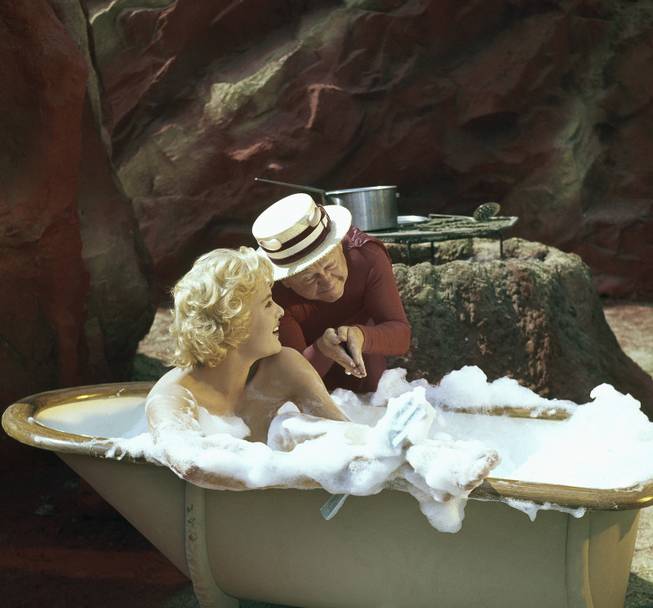 Mickey Rooney wearing costume for role in movie "The Private Lives of Adam & Eve." Rooney plays the part of the devil. Girl in the tub is British Actress Joan Wilkinson. The movie story is about people stranded by a flood on the way to Reno, Nevada, with bus passengers becoming Adam, Eve, and the devil in a dream. Within the Garden of Eden the story has Vaudevillian skits involving Mickey Rooney as Satan. This photo is dated September 8, 1959.