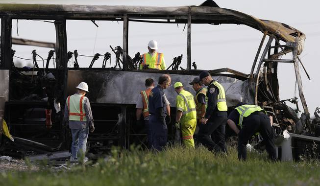 Officials and California Highway Patrol Officers look over the remains of a tour bus that was struck by a FedEx truck on Interstate 5 Thursday in Orland, Calif., Friday, April 11, 2014. At least ten people were killed and dozens injured in the fiery crash between the truck and a bus carrying high school students on a visit to a Northern California College.