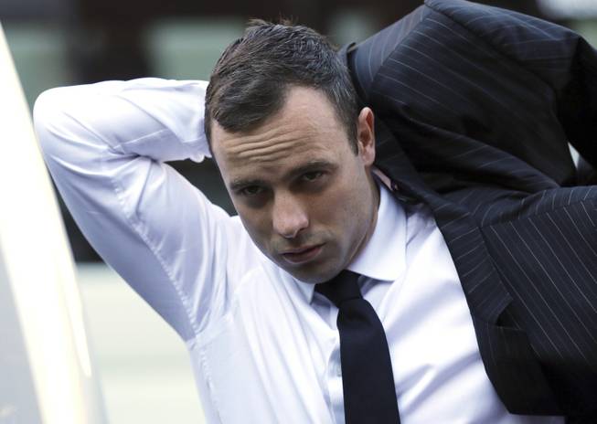 Oscar Pistorius puts on his jacket as he arrives at the high court in Pretoria, South Africa, Friday, April 11, 2014. The chief prosecutor laughed scornfully at an answer from Pistorius during the Olympic athlete's murder trial Thursday, mocking the man who shot his girlfriend. Pistorius is charged with murder for the shooting death of his girlfriend, Reeva Steenkamp, on Valentine's Day in 2013.