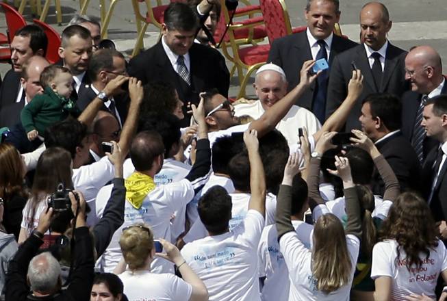 Pope Francis poses for pictures with faithful at the end of a Palm Sunday service in St. Peter's Square, at the Vatican, Sunday, April 13, 2014. Pope Francis, marking Palm Sunday in a packed St. Peter's Square, ignored his prepared homily and spoke entirely off-the-cuff in a remarkable departure from practice. Later, he hopped off his popemobile to pose for "selfies" with young people in the crowd. In his homily, Francis called on people, himself included, to look into their own hearts to see how they are living their lives.