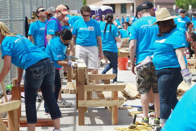 Volunteers put together benches and tables as they work on building a KaBoom playground for Child Haven Tuesday, April 15, 2014. Clark County Department of Family Services and Chicanos Por La Causa teamed up with volunteers from DirectTV and local businesses to rebuild the playground that was closed in 2012.
