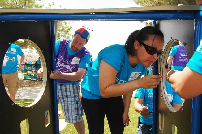 Kevin Nelson and Kristal Jacobs assemble a section of a play structure as volunteers work on building a KaBoom playground for Child Haven Tuesday, April 15, 2014. Clark County Department of Family Services and Chicanos Por La Causa teamed up with volunteers from DirectTV and local businesses to rebuild the playground that was closed in 2012.