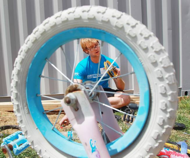 Marc Chmiel fixes a bike as he and other volunteers work on building a KaBoom playground and sprucing up other elements for Child Haven Tuesday, April 15, 2014. Clark County Department of Family Services and Chicanos Por La Causa teamed up with volunteers from DirectTV and local businesses to rebuild the playground that was closed in 2012.