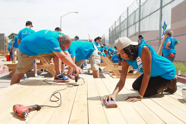 Tiffany Dail sands a platform as volunteers work on building a KaBoom playground for Child Haven Tuesday, April 15, 2014. Clark County Department of Family Services and Chicanos Por La Causa teamed up with volunteers from DirectTV and local businesses to rebuild the playground that was closed in 2012.