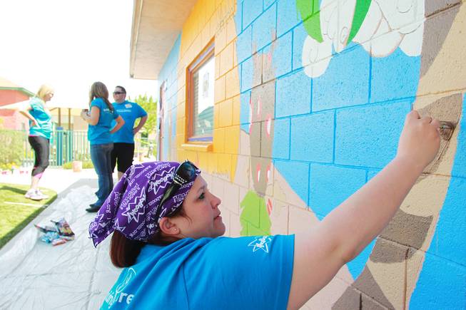 Amanda Johnston works on a mural as volunteers work on building a KaBoom playground for Child Haven Tuesday, April 15, 2014. Clark County Department of Family Services and Chicanos Por La Causa teamed up with volunteers from DirectTV and local businesses to rebuild the playground that was closed in 2012.