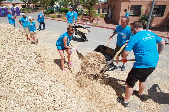 Volunteers fill a wheelbarrow with wood chips as they work on building a KaBoom playground for Child Haven Tuesday, April 15, 2014. Clark County Department of Family Services and Chicanos Por La Causa teamed up with volunteers from DirectTV and local businesses to rebuild the playground that was closed in 2012.