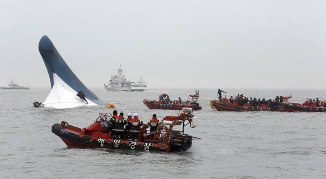 South Korean coast guard officers try to rescue passengers from ferry Sewol in the water off the southern coast near Jindo, south of Seoul, South Korea, Wednesday, April 16, 2014. Dozens of boats, helicopters and divers scrambled Wednesday to rescue more than 470 people, including 325 high school students on a school trip, after the ferry sank off South Korea's southern coast.