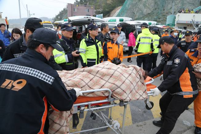 A rescued passenger from a ferry sinking off South Korea's southern coast, is carried by rescue teams on his arrival at Jindo port in Jindo, south of Seoul, South Korea, Wednesday, April 16, 2014. Dozens of military boats and helicopters scrambled Wednesday to rescue more than 470 people, including 325 high school students on a school trip, after the ferry sank off South Korea's southern coast, officials said.