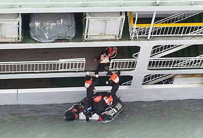In this photo released by the South Korean Coast Guard via Yonhap News Agency, South Korean coast guard officers rescue passengers from a sinking ferry off the southern coast near Jindo, south of Seoul, South Korea, Wednesday, April 16, 2014. A ferry carrying 459 people, mostly high school students on an overnight trip to a tourist island, sank off South Korea's southern coast on Wednesday, leaving nearly 300 people missing despite a frantic, hours-long rescue by dozens of ships and helicopters.