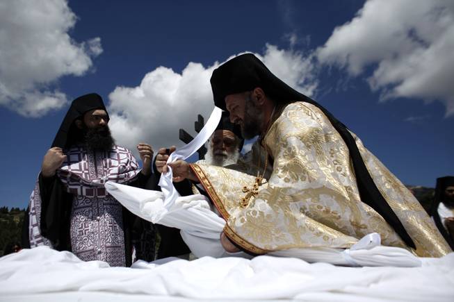 A Greek Orthodox priest wraps an icon of the body of Jesus with a sheet during a Good Friday reenactment of Christ being taken down from the crucifix, at the Penteli Monastery, near Athens, on Friday, April 18, 2014. More than 250 million Orthodox Christians worldwide will celebrate Easter this year on Sunday, April 20.