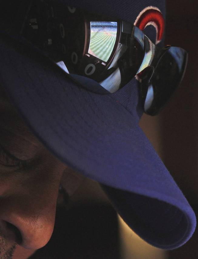 In this April 10, 2014, photo, scoreboard operator Darryl Wilson keeps up with the game from inside Wrigley Field's iconic scoreboard during a baseball game between the Pittsburgh Pirates and the Chicago Cubs, in Chicago. Wilson mans the two top floors, little more than scaffolding of the three-level scoreboard, tracking scores from around baseball and changing scores and the uniform numbers of pitchers as managers in those games bring in relievers.