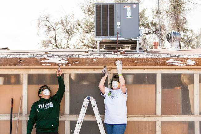 Volunteers Bailey Davis and Karen Edmondson, right, scrape paint in preparation for painting the home of former magician Gary Darwin, who lost his leg to diabetes, as part of the Rebuilding Together Southern Nevada's annual neighborhood rebuilding event in Las Vegas Saturday, April 26, 2014.