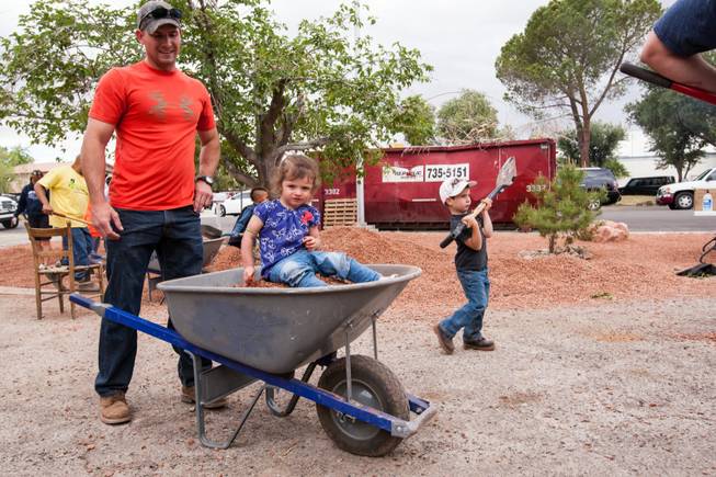 Jeremiah Blower prepares to move rocks while volunteering with his 19-month-old daughter, Beverly, and 4-year-old son, Everett, at the home of photographer Robert Scott Hooper and wife Theresa Hooper as part of the Rebuilding Together Southern Nevada's annual neighborhood rebuilding event in Las Vegas Saturday, April 26, 2014.