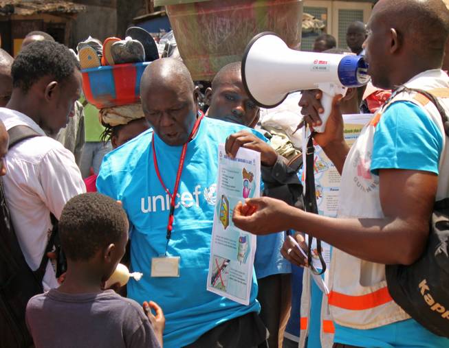 In this file photo taken on March 31, 2014, UNICEF health workers teach people about the Ebola virus and how to prevent infection, in Conakry, Guinea. The Ebola outbreak in West Africa has claimed some hundreds of lives, and is almost always fatal with horrific suffering including bursting blood vessels, there is no vaccine or known effective treatment, but it seems a handful of infected people have survived. However those who survive the horrors of the disease have to cope with being outcast by everybody, such is the fear people have of Ebola.