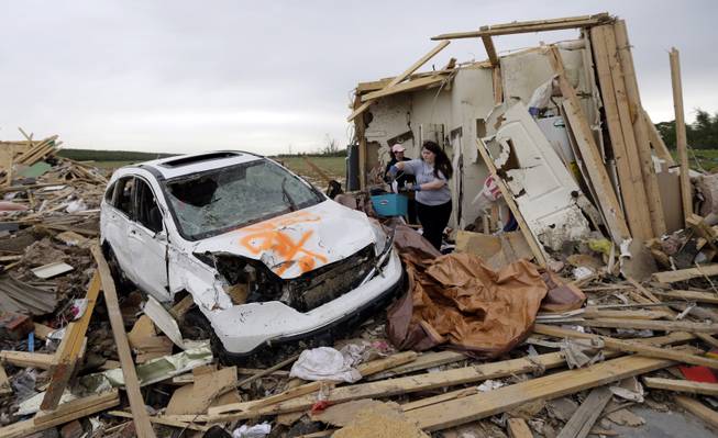 Haley Hracke, front, and Melissa Nichols, search for belongings at a friend's home that was destroyed by Sunday's tornado, Tuesday, April 29, 2014, in Vilonia, Ark. A dangerous storm system that spawned a chain of deadly tornadoes over three days flattened homes and businesses, forced frightened residents in more than half a dozen states to take cover and left tens of thousands in the dark Tuesday morning.