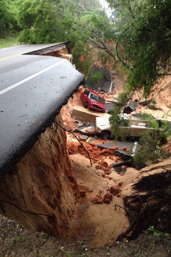 A car lies at the bottom of a ravine after the Scenic Highway collapsed near Pensacola, Fla., Wednesday April 30, 2014. Heavy rains and flooding have left people stranded in houses and cars in the Florida Panhandle and along the Alabama coast. According to the National Weather Service, an estimated 15-20 inches of rain has fallen in Pensacola in the past 24 hours.