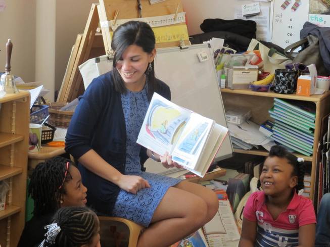 In this April 10, 2014, file photo, student teacher Franchesca Moreno, 21, reads to Andreanna Thomas, 6, right, and Alana Cawthon, upper left, at Bennett Park Montessori School in Buffalo, N.Y. Moreno is among the first future New York teachers required to pass a kind of "bar exam" to become professionally certified.