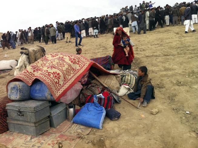 Survivors sit with their possessions near the site of Friday's landslide that buried Abi-Barik village in Badakhshan province, northeastern Afghanistan on Saturday, May 3, 2014. Afghan rescuers and volunteers armed with shovels and little more than their bare hands dug through the mud Saturday after a massive landslide swept through a village the day before, turning it into an earthen tomb holding hundreds of bodies, officials said. Aid groups struggle to bring food, shelter and water to the region, as the government tries to ascertain just how many people were killed.