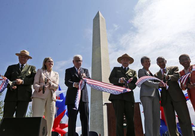 From left to right: Robert A. Vogel, Superintendent of the National Mall and Memorial Parks; Caroline L. Cunningham, President of the Trust for the National Mall; David M. Rubinstein, co-founder and co-chief executive officer of The Carlyle Group; Jonathan B. Jarvis, Director of the National Park Service; Interior Secretary Sally Jewell; White House Counsel John Podesta, and Del. Eleanor Holmes Norton, D-D.C., cut a ribbon at the Washington Monument in Washington, Monday, May 12, 2014, during a ceremony to celebrate its re-opening. The monument, which sustained damage from an earthquake in August 2011, reopened to the public today. (AP Photo)