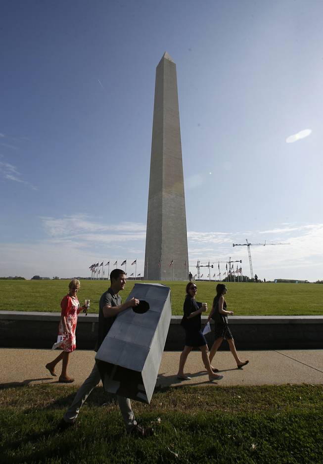 Steven Avila, an Interior Department employee, carries a Washington Monument costume as he arrives at the Washington Monument in Washington, Monday, May 12, 2014, ahead of a ceremony to celebrate its re-opening. The monument, which sustained damage from an earthquake in August 2011, is reopening to the public today. Avila made the costume to show his support for the re-opening of the monument.