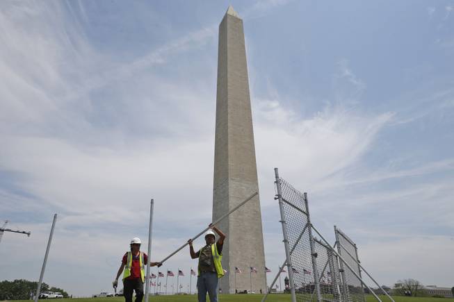 Workers Julio Dichis, right, and Jose Oreyana remove the fencing which closed the Washington Monument off to the public during renovations Washington, Friday, May 9, 2014. The monument, which sustained damage from an earthquake in August 2011, will re-open to the public on Monday, May 12, 2014.