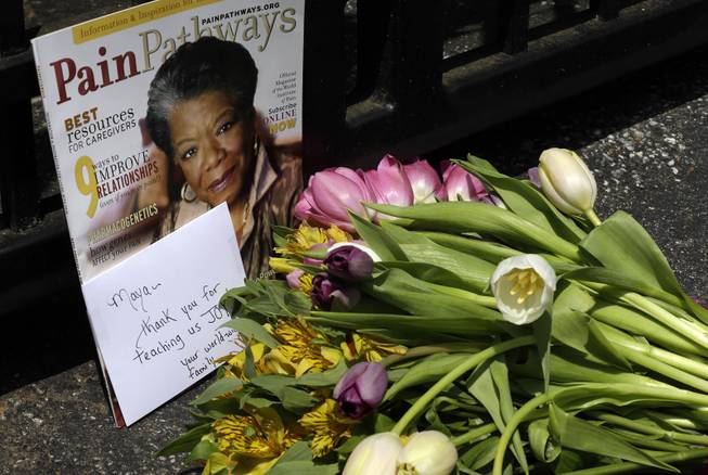 A bouquet of flowers and a magazine showing Maya Angelou on the cover lies outside a gate at the home of Angelou in Winston-Salem, N.C., Wednesday, May 28, 2014. Angelou, a Renaissance woman and cultural pioneer, has died, Wake Forest University said in a statement Wednesday. She was 86.
