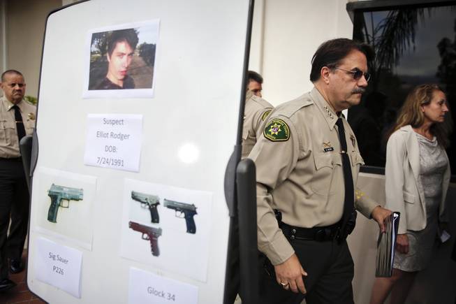 Santa Barbara County Sheriff Bill Brown, right, walks past a board showing the photos of suspected gunman Elliot Rodger and the weapons he used in Friday night's mass shooting that took place in Isla Vista, Calif., after a news conference on Saturday, May 24, 2014, in Santa Barbara, Calif.