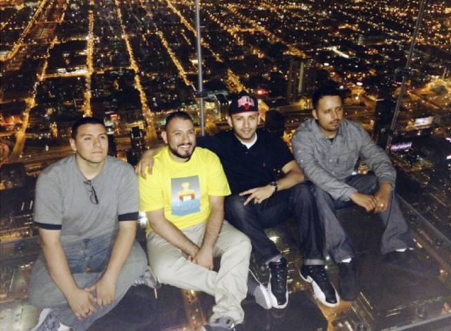 This Wednesday, May 28, 2014 photo provided by Alejandro Galibay shows Galibay, 23, of Stockton, Calif., second from right, sitting with his brother Ernesto, right, and cousins David Cazares, left, and Antonio Saldana on The Ledge, a popular tourist attraction on the 103rd floor of the Willis Tower in Chicago shortly before the coating protecting the glass bay they were sitting on started to crack. Garibay said Thursday, May 29, he knows now he wasn't in danger but when he first heard what sounded like breaking ice, he thought he was going to die.