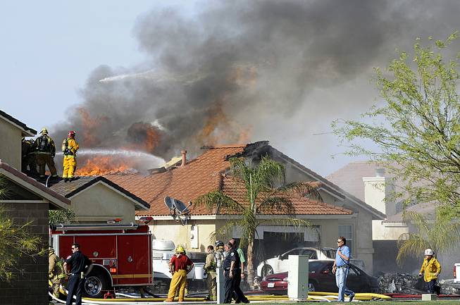 This photo shows the site of a military jet that crashed on a residential street in Imperial, Calif., setting two homes on fire Wednesday, June 4, 2014. Lance Cpl. Christopher Johns, a U.S. Marines spokesman, says the jet was a Harrier from Marine Corps Air Station in Yuma, Ariz.