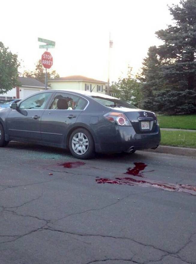 A car sits on a road with it's windows shot out and blood on the ground in Moncton, New Brunswick on Wednesday, June 4, 2014. The Royal Canadian Mounted Police says three of its officers were killed in Moncton, New Brunswick by a man armed with guns and two other officers were injured as the Mounties conducted a manhunt across the city's north end on Wednesday night for the shooter.
