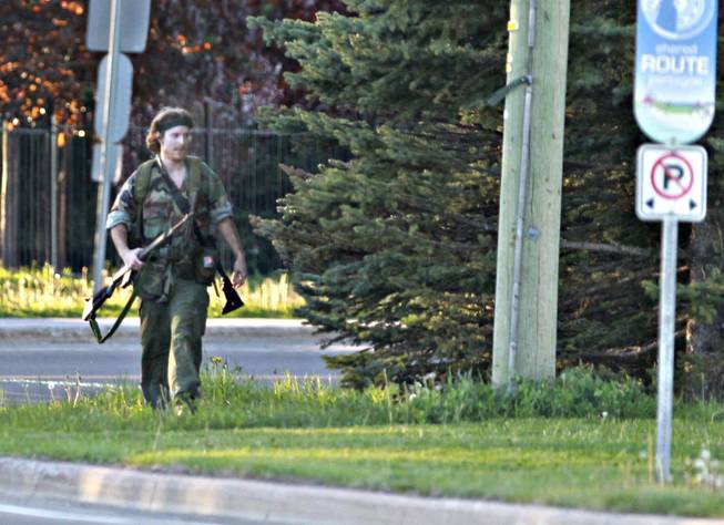 A heavily armed man that police have identified as Justin Bourque walks on Hildegard Drive in Moncton, New Brunswick, on Wednesday, June 4, 2014, after several shots were fired in the area. The man, suspected of killing three Royal Canadian Mounted Police officers, was spotted three times Thursday but has so far eluded a massive manhunt, police said.