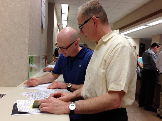 Mark Williams, left, and Chrisopher Martell, right, fill out an application for a marriage license at the Milwaukee County Clerk's office Friday, June 6, 2014, in Milwaukee. Same-sex couples began getting married in Wisconsin on Friday shortly after a federal judge struck down the state's gay marriage ban and despite confusion over the effect of the ruling.