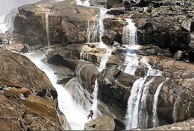 In this May 28, 2014, still image from video provided by the National Park Service, a backpacker who narrowly avoided plunging to his death from a gorge at the bottom of Upper Yosemite Fall at Yosemite National Park, in Calif., is hoisted to safety by a helicopter rescue crew.