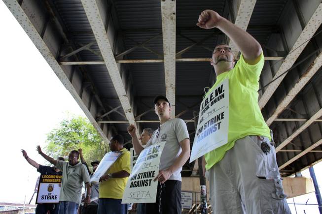 Members of the Brotherhood of Locomotive Engineers and Trainmen (BLET) union and members of the International Brotherhood of Electrical Workers (IBEW) wave to motorist while walking a picket line outside the Roberts Avenue rail yard in Philadelphia on Saturday, June 14, 2014, after the two unions went on strike at midnight Friday. Pennsylvania Gov. Tom Corbett asked President Barack Obama on Saturday to intervene the dispute between the Southeast Pennsylvania Transportation Authority and its engineers and electricians unions. He did, and workers were expected to return to their jobs.