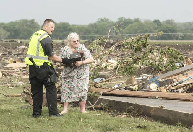 Ruth Labenz is assisted to safety by a Stanton County Sherriff's officer after her home was destroyed in the town of Pilger, Neb. Monday, June 16, 2014. At least one person is dead and at least 16 more are in critical condition after two massive tornadoes swept through northeast Nebraska on Monday.